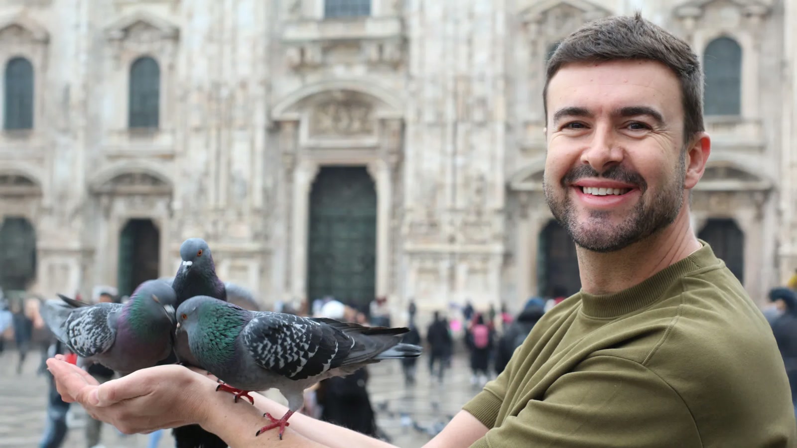 Cena ilustrativa: Pardal pousado no chão de uma praça urbana, com uma pessoa de costas ao fundo, sem texto sobreposto, no trecho “Por que ninguém sabe a explicação”